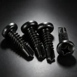 Black cross-recessed self-drilling screws on a dark industrial surface