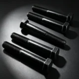 Black hex head fasteners arranged on a dark inspection surface