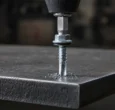 Hex washer head self-drilling screw with a long drill point starting into a thick steel plate