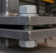 Heavy hex structural bolt with matching nut and hardened washer clamping thick structural steel plates