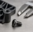 Thread-forming screw beside a molded plastic boss on an inspection bench
